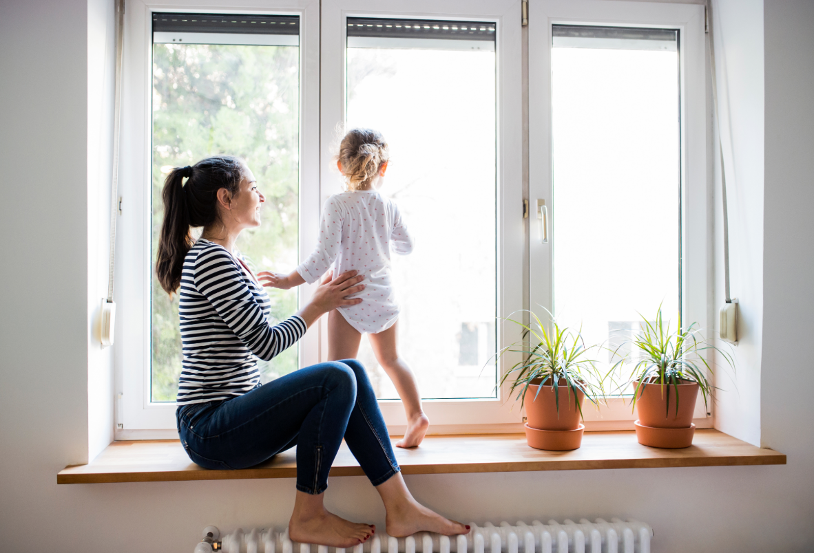 Mother with young daughter in front of window