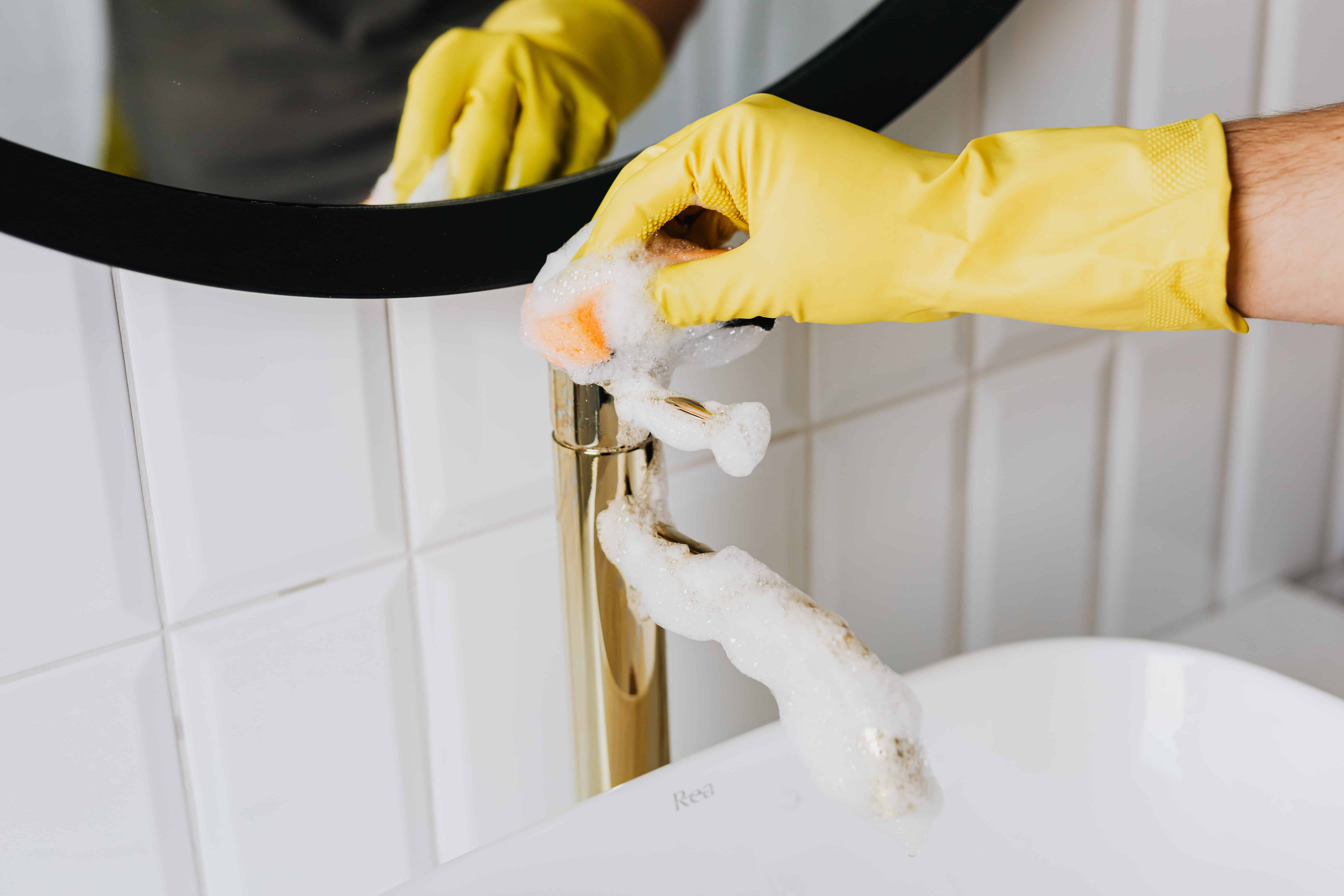 Dust Queen epmloyee cleaning bathroom plumbing fixtures as part of a residential clean.